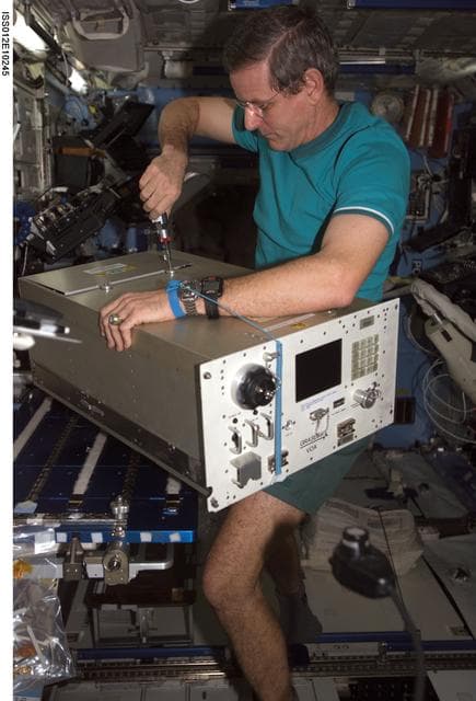 NASA image: McArthur replaces the top panels on the VOA during In-flight Maintenance on Expedition 12