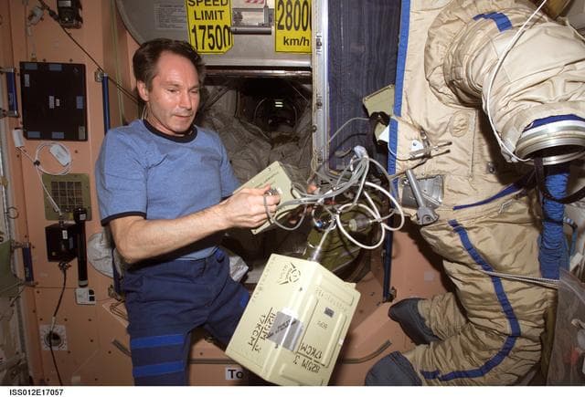 NASA image: Tokarev puts battery boxes inside the Orlan suit as he assembles the RadioSkaf microsatellite on Expedition 12