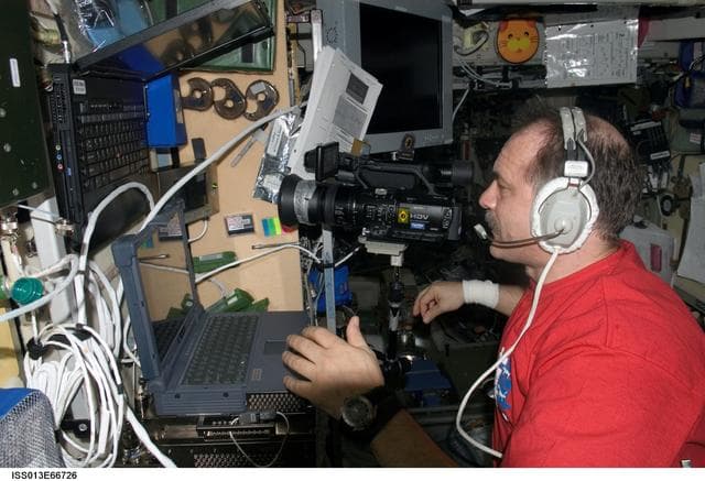 NASA image: Vinogradov uses a Sony HD Video Camcorder and laptop computer in the SM during Expedition 13
