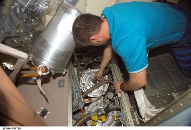 NASA image: Replacing E-K pre-treat container and hose in АСУ system
