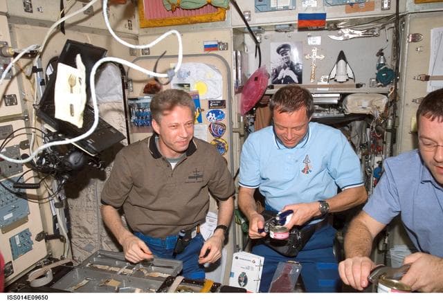 NASA image: STS-116 and Expedition 14 crews share a meal in the Zvezda Service module