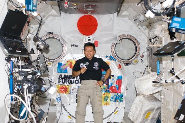 NASA image: Wakata with handset and Ambitious Fukuoka Banner