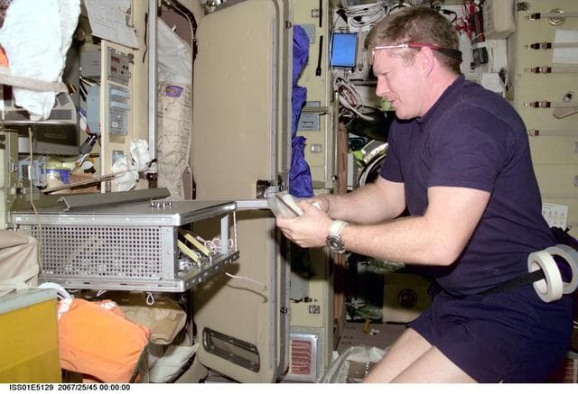 NASA image: Shepherd in Service Module working on ward room table