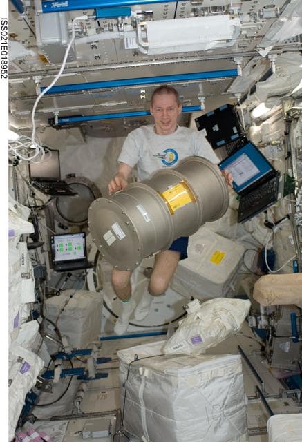 NASA image: Expedition 21 Commander De Winne poses for a photo with a MSL FLSS