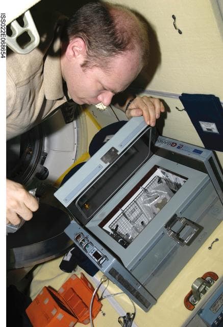 NASA image: Kotov collects samples from the Bioscience Experiment ASEPTIC (BTKh-39) in the MRM2 during Joint Operations