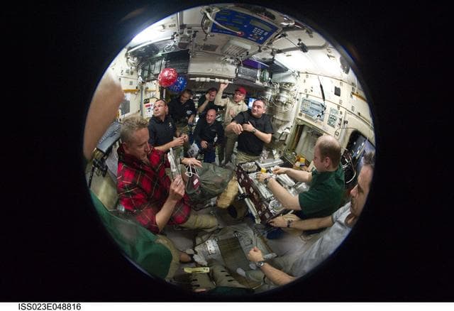 NASA image: Fisheye View of Crewmembers Sharing a Meal in the SM