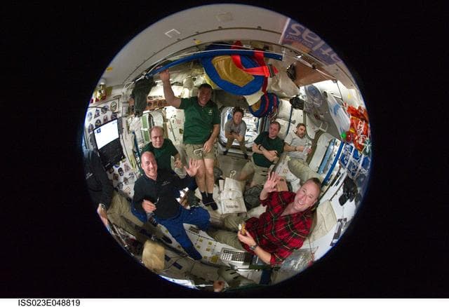 NASA image: Fisheye View of Crewmembers Sharing a Meal in the SM