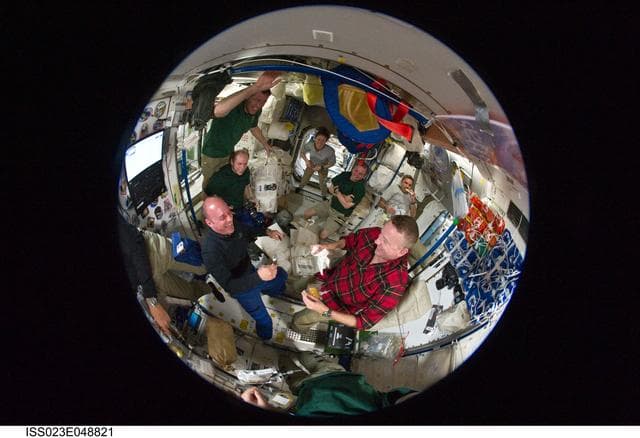 NASA image: Fisheye View of Crewmembers Sharing a Meal in the SM