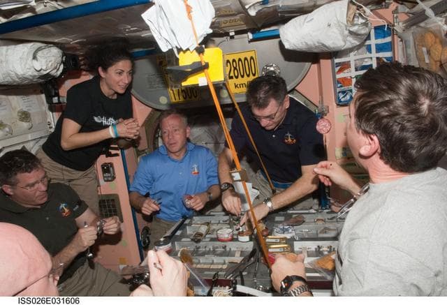 NASA image: Expedition 26 and STS-133 Crewmembers enjoy meal in the Node 1