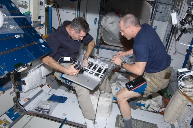 NASA image: Burbank and Pettit stow camera equipment in a container in the Node 2