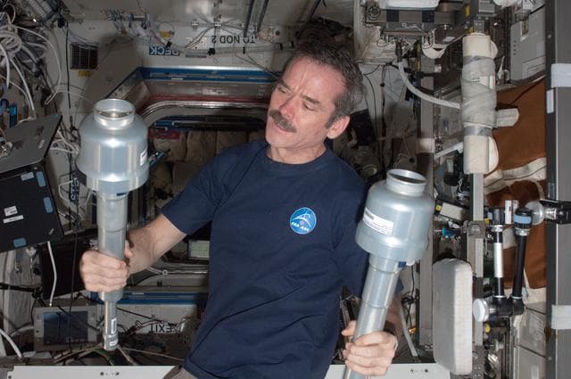 NASA image: Hadfield holds two MSL SQF Sample Cartridge MPCs in the U.S. Laboratory