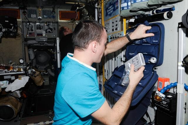 NASA image: Ryazanskiy places monitor in bag