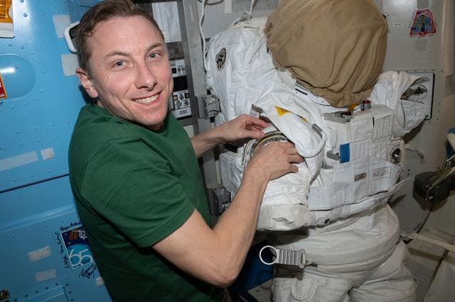 NASA image: NASA astronaut Woody Hoburg prepares a spacesuit for a spacewalk