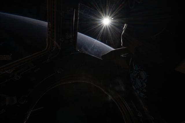 The setting sun highlights Earth's horizon