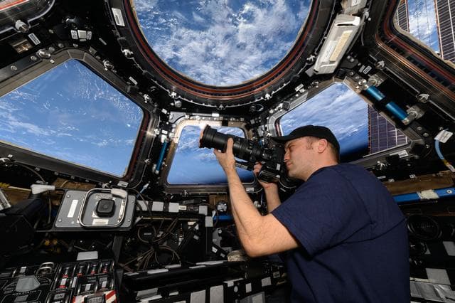 NASA image: Astronaut Matthew Dominick points his camera out a window on the cupola