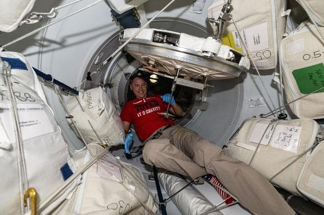 NASA image: Astronaut Nick Hague in the vestibule between the space station and the Dragon cargo spacecraft