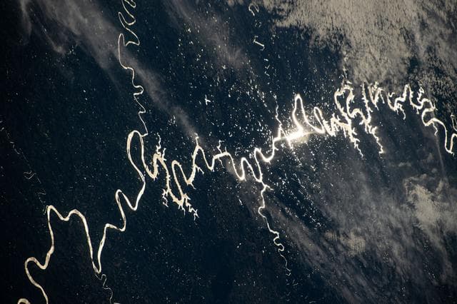 NASA image: The Sun's glint beams off a river in South America