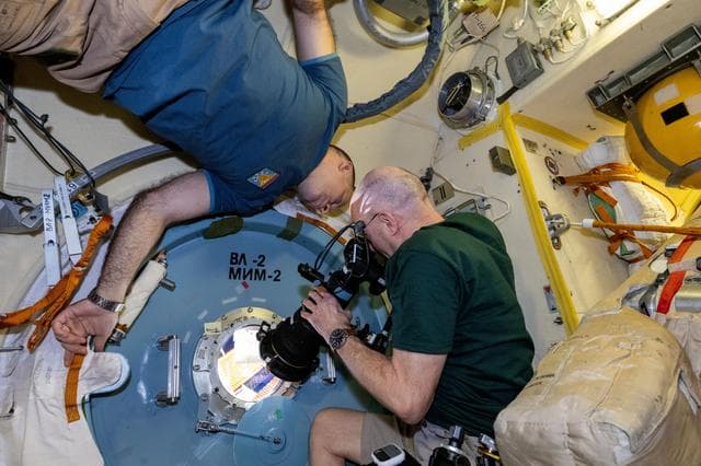 NASA image: Astronaut Don Pettit points a camera outside a window for a sun photography session