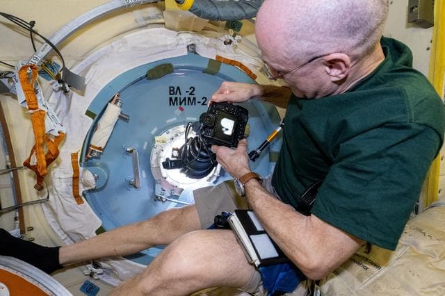 NASA image: Astronaut Don Pettit points a camera outside a window for a sun photography session