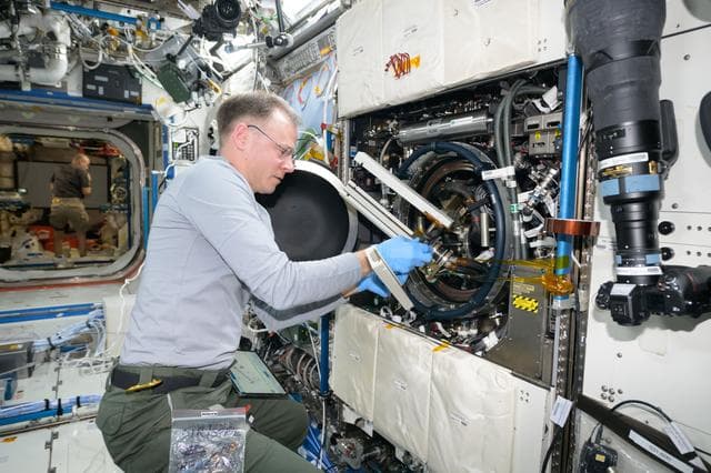 NASA image: Astronaut Nick Hague swaps samples of materials to observe how they burn in weightlessness