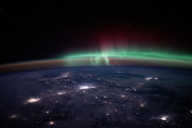 NASA image: City lights dot the Canadian landscape underneath an aurora
