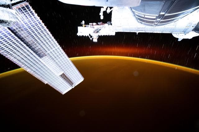 NASA image: Star trails and an atmospheric glow blanket Earth's horizon