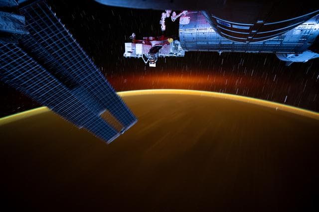 NASA image: Star trails and an atmospheric glow blanket Earth's horizon
