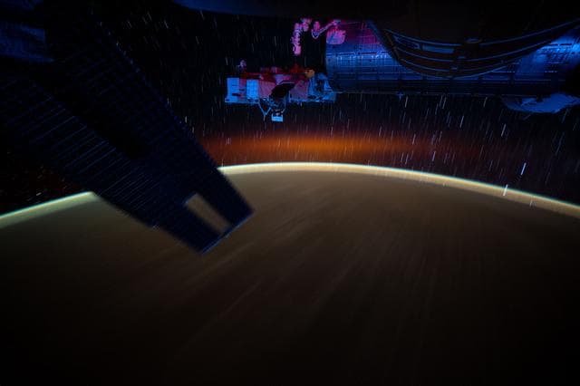 NASA image: Star trails and an atmospheric glow blanket Earth's horizon