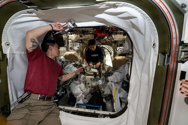 Astronauts Jonny Kim and Takuya Onishi set up a pair of spacesuits