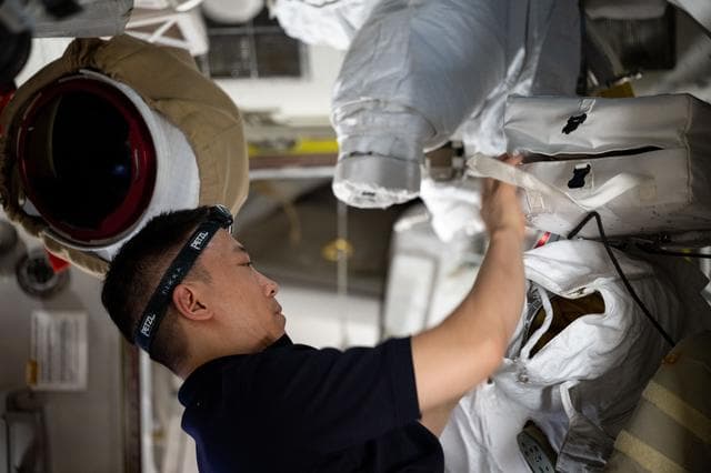 NASA image: NASA astronaut Jonny Kim works on spacesuit maintenance