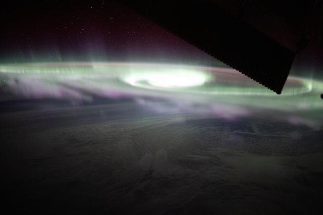 NASA image: The aurora australis swirls over a cloudy Pacific Ocean