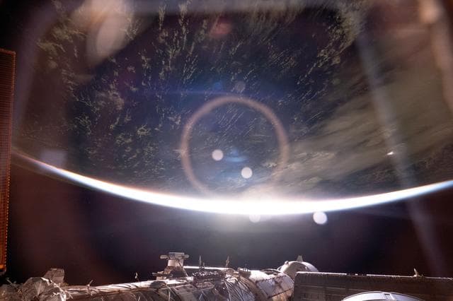 NASA image: The light from an orbital sunrise refracts through a window inside the International Space Station