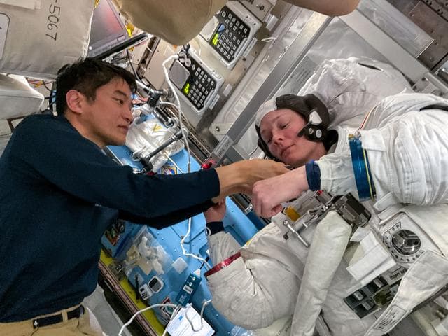 NASA image: Astronaut Takuya Onishi assists Nichole Ayers as she tries on a spacesuit