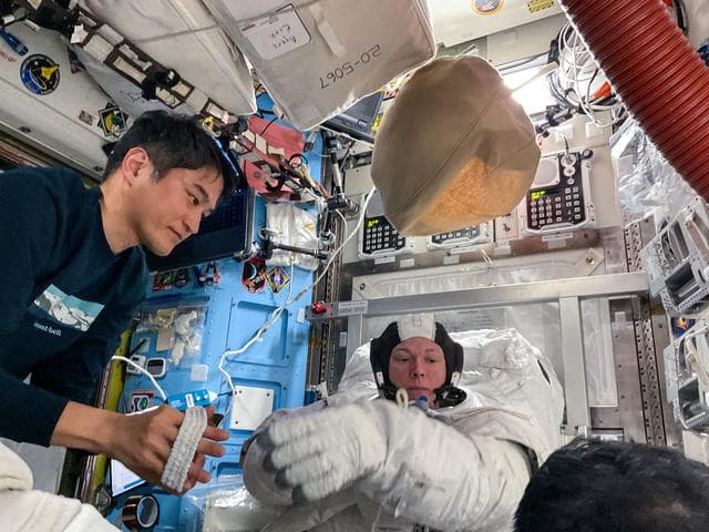 NASA image: Astronaut Takuya Onishi assists Nichole Ayers as she tries on a spacesuit