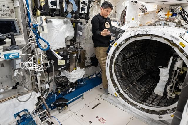 NASA image: JAXA astronaut Takuya Onishi prepares to retract a slide table that contains research hardware
