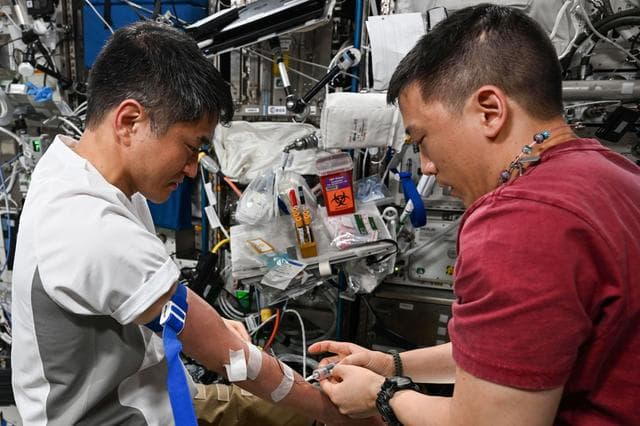NASA image: Astronaut Jonny Kim draws a blood sample from astronaut Takuya Onishi