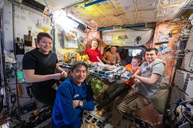 NASA image: Expedition 73 crew members pose for a portrait during dinnertime