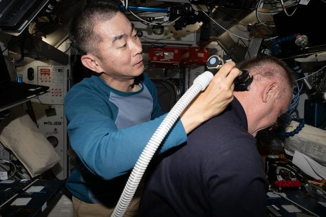 NASA image: JAXA astronaut Kimiya Yui trims NASA astronaut Mike Fincke's hair aboard the International Space Station