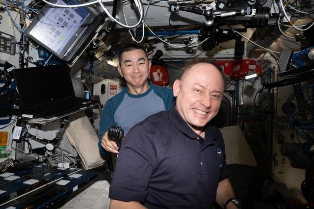 NASA image: Astronauts Kimiya Yui and Mike Fincke smile for a portrait during a haircut
