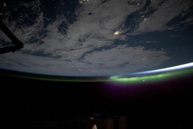 NASA image: A wispy aurora caps Earth's horizon as an orbital sunrise illuminates the atmosphere