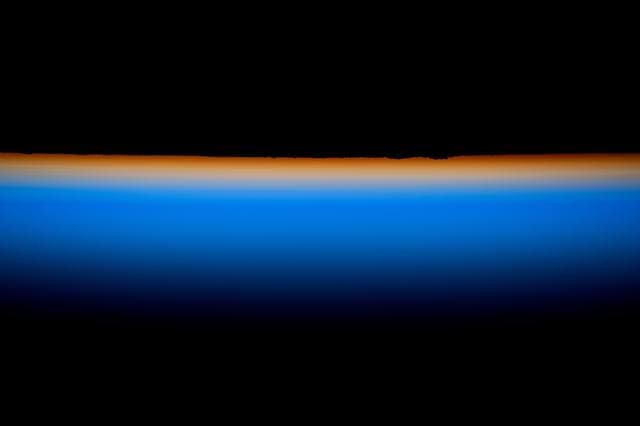 NASA image: The last rays of an orbital sunset outline Earth’s horizon with a thin orange hue