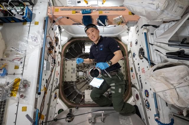 NASA astronaut Jonny Kim prepares to open the hatch to the Cygnus XL spacecraft