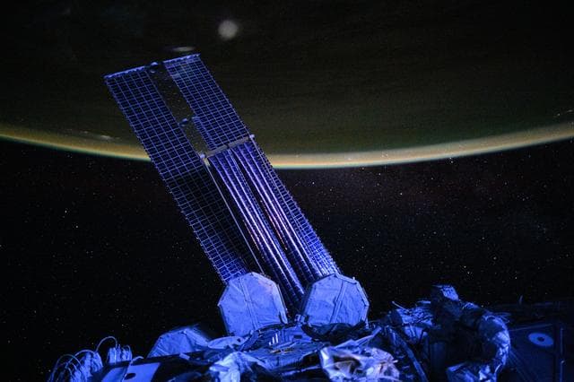 NASA image: Moonlit, violet-hued view of the International Space Station’s main solar arrays