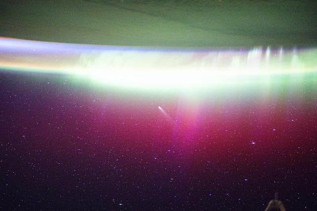 NASA image: A bright, neon-like aurora radiates above Earth and seemingly absorbs Comet Lemmon 