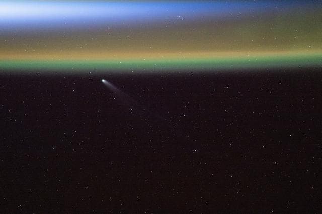 NASA image: Comet Swan appears above Earth’s yellow-green airglow just before an orbital sunrise