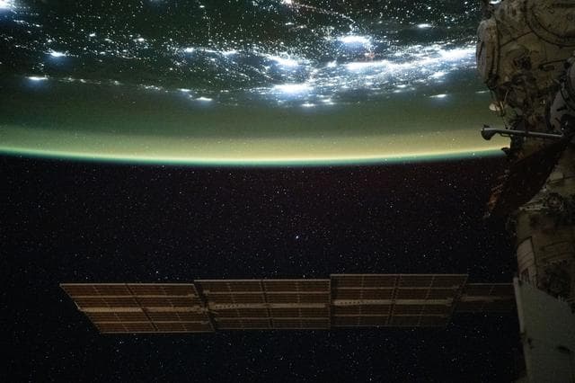 NASA image: A yellow-green airglow blankets the city lights of North America