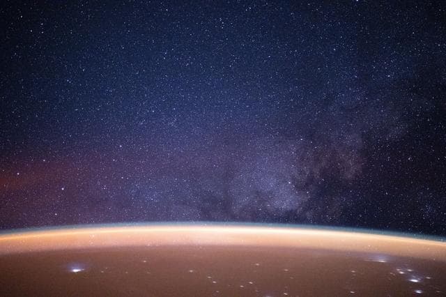 NASA image: A reddish airglow blankets Earth beneath the Milky Way