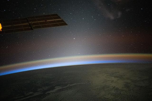 NASA image: A red-yellow airglow blankets Earth as the last rays of an orbital sunset illuminate the atmosphere