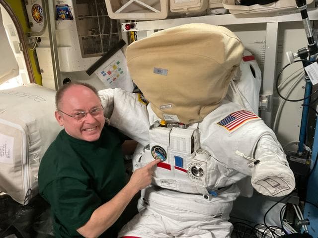 NASA image: NASA astronaut Mike Fincke poses next to a spacesuit