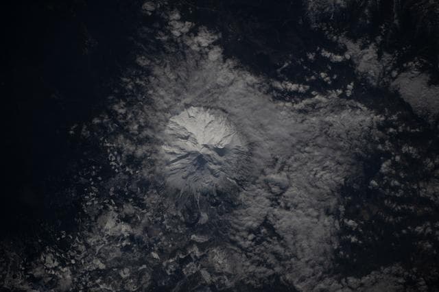 NASA image: The snow-capped Mount Shasta is surrounded by clouds